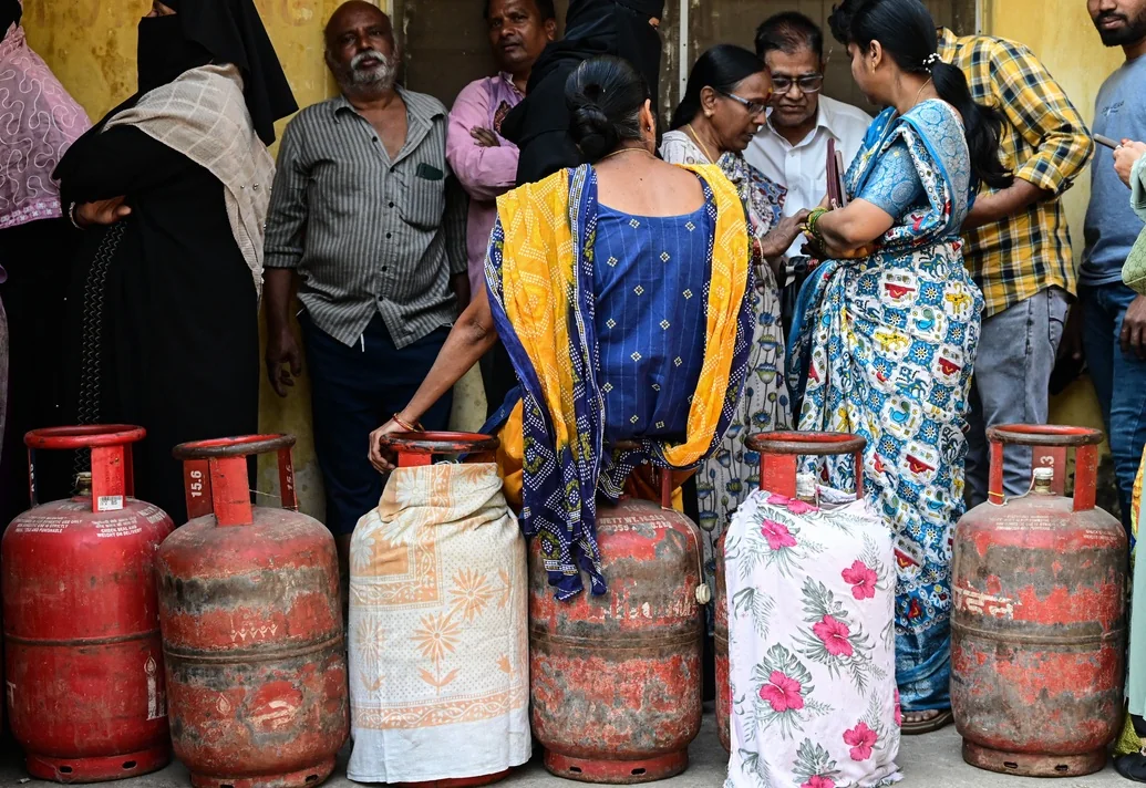 A woman rests on an LPG cylinder while waiting at a Hyderabad gas agency.
