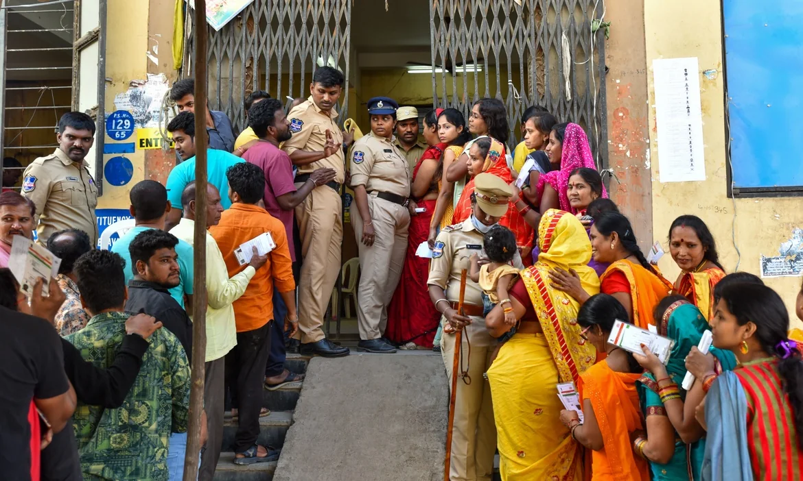 Voters wait outside a polling station in Telangana.