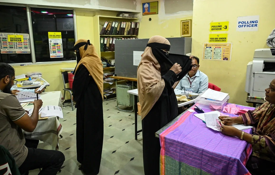 Polling officials check voter details at a polling booth in Telangana.