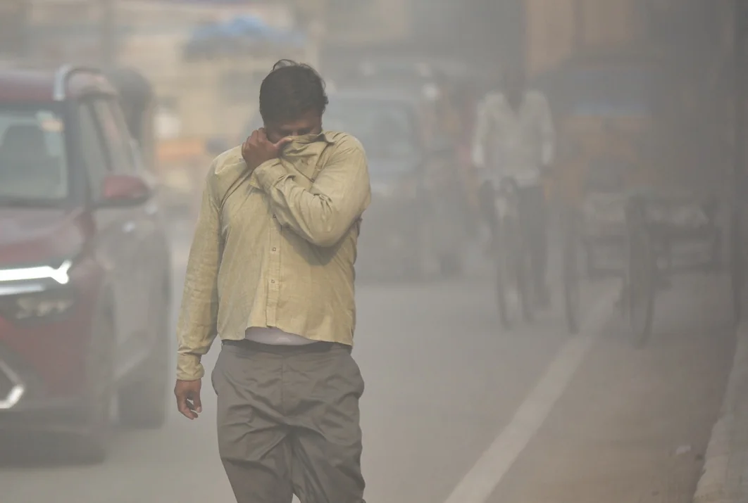 A pedestrian covers his face in dust near a construction site in Hyderabad.