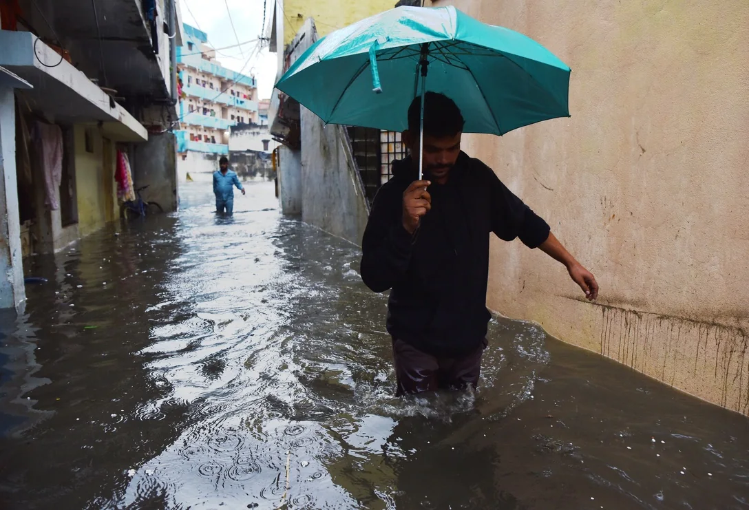 A pedestrian uses an umbrella while walking through a flooded street in Hyderabad.