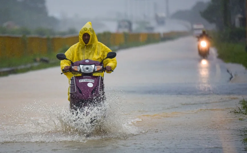 A commuter rides through floodwater during rainfall ahead of Cyclone Montha in Nellore.