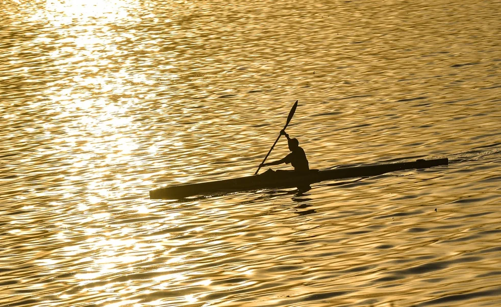 A kayaker paddles on Hussain Sagar Lake at sunset in Hyderabad.